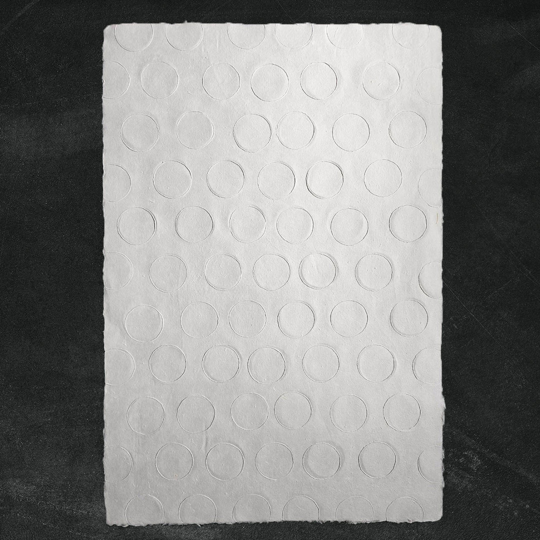 A sheet of medium-weight handmade paper crafted from mulberry fiber at Kozo Studio, showcasing elegant embossed circles and artisanal texture.