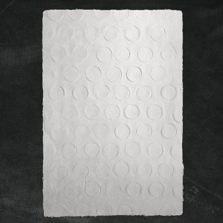 A sheet of medium-weight handmade paper crafted from mulberry fiber at Kozo Studio, showcasing elegant embossed circles and artisanal texture.