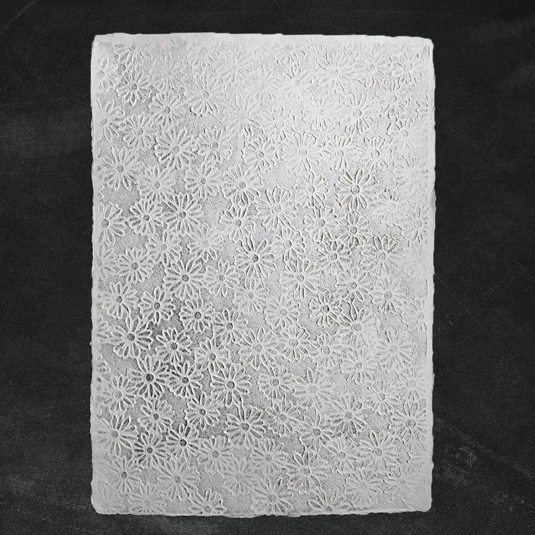 Close-up of handmade paper with intricate lace embossing and floral designs, crafted by Kozo Studio using traditional mulberry paper and Rakusui methods.