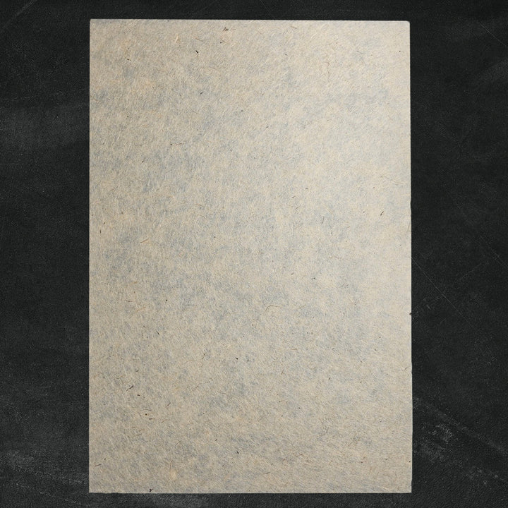 Eco-friendly handmade paper from Kozo Studio made with jute and mulberry pulp, featuring a light brown hue and unique fibrous surface ideal for creative projects.
