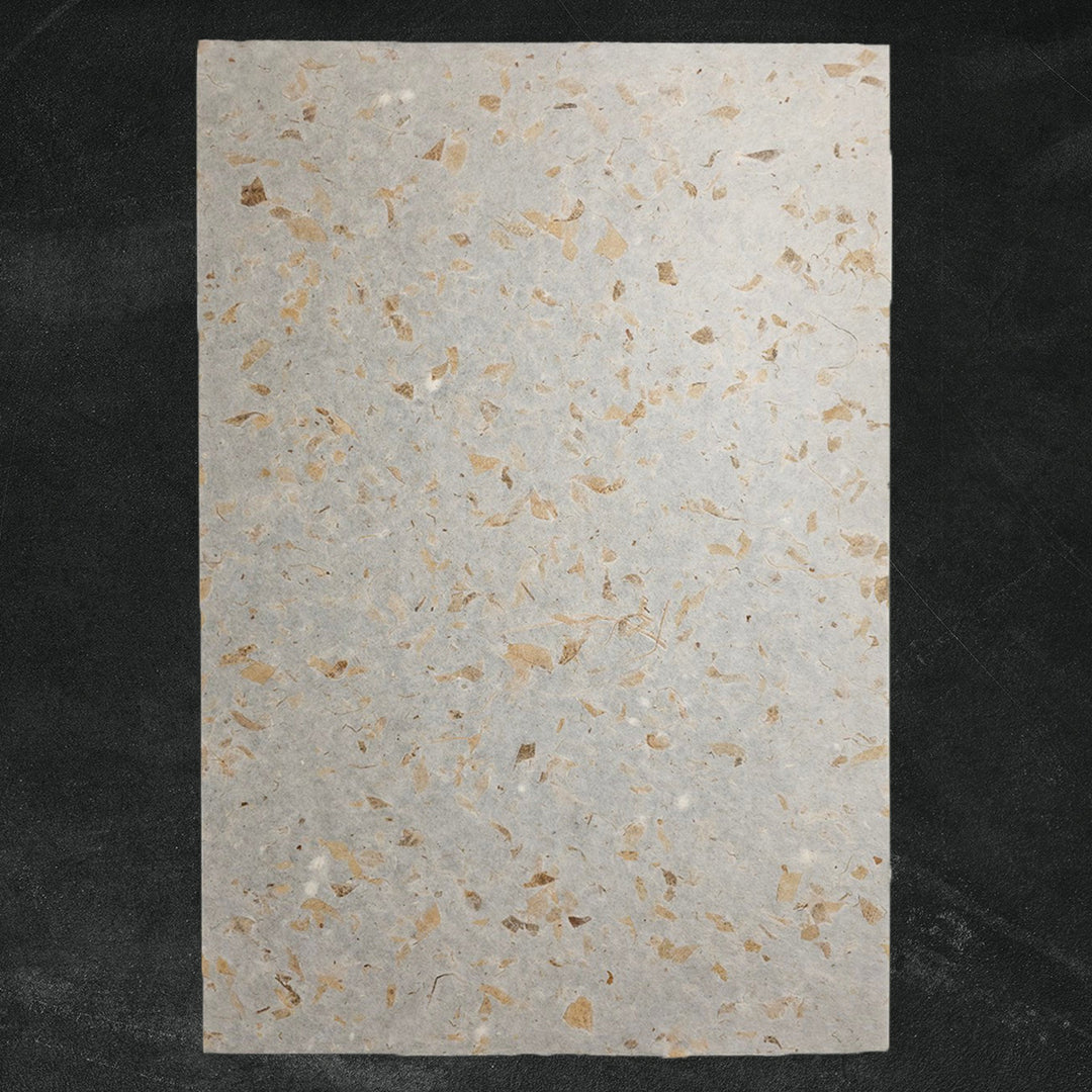 Handmade paper crafted by Kozo Studio using mulberry fibers and dried mango leaves, capturing its semi-translucent, eco-friendly texture in soft natural tones.