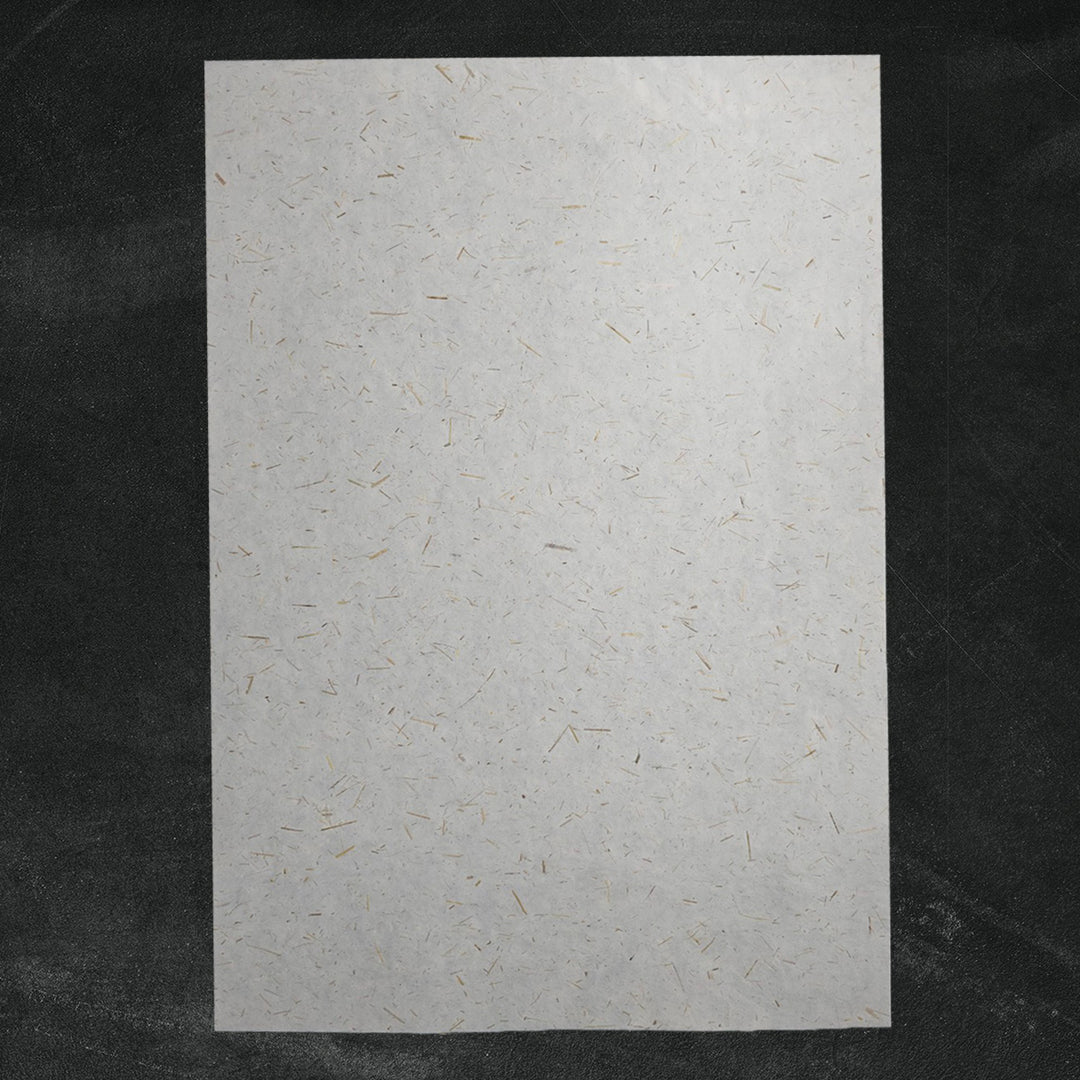 Handmade paper from Kozo Studio featuring semi-translucent mulberry fibers and rice straw confetti, perfect for eco-friendly decorative use.