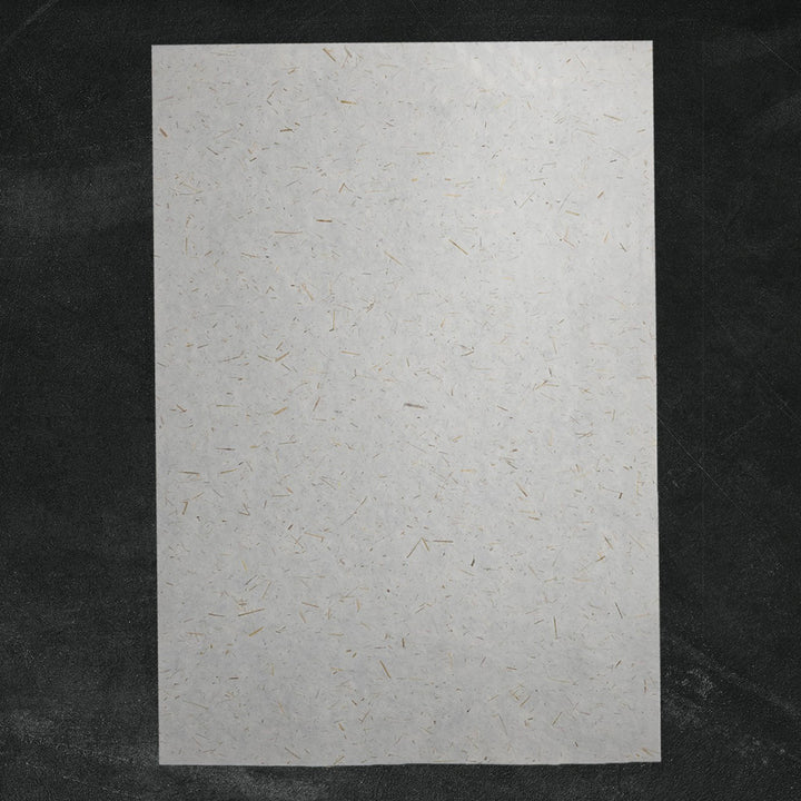 Handmade paper from Kozo Studio featuring semi-translucent mulberry fibers and rice straw confetti, perfect for eco-friendly decorative use.