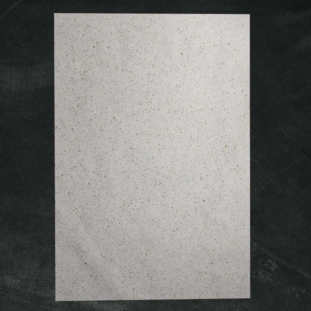 Decorative Tobac Confetti Kozo handmade paper by Kozo Studio, made from mulberry fibers and embedded with natural leaf confetti for a unique speckled appearance.