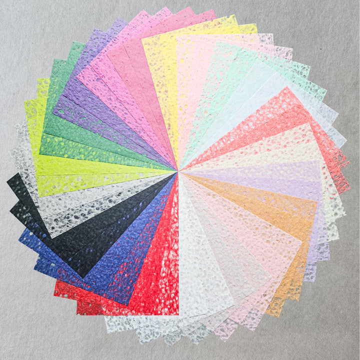 The Assorted A4 Rakusui Mulberry Paper Set (40 Sheets) by Kozo Studio displays fan-shaped, lace-textured sheets in a range of colors radiating from the center against a neutral gray background.