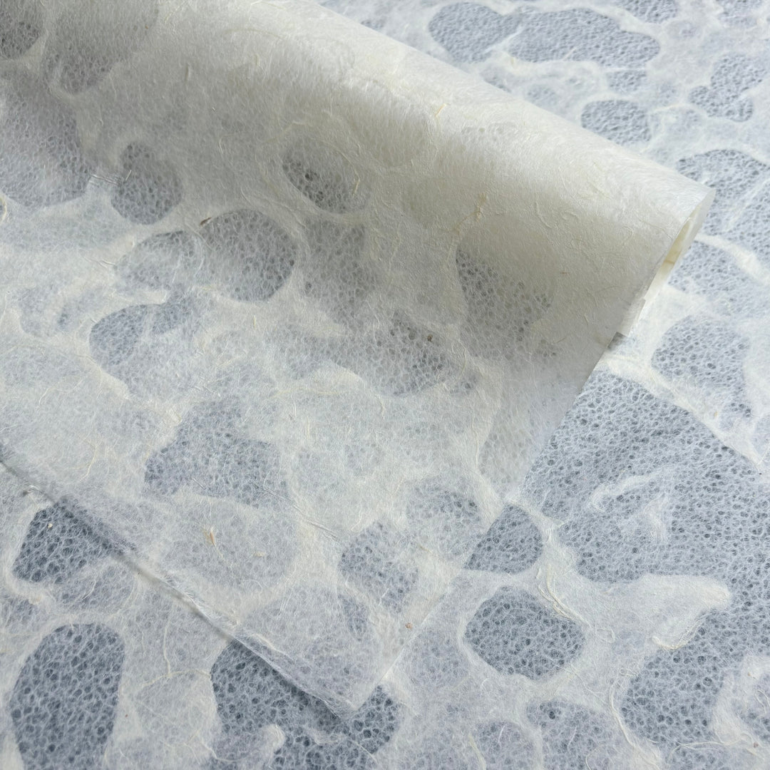 A close-up of Kozo Studios Tidal Lace Kozo Paper (Unryu) shows its semi-translucent, textured surface with an organic pattern and embedded fibers, highlighting the eco-conscious design and natural appeal.