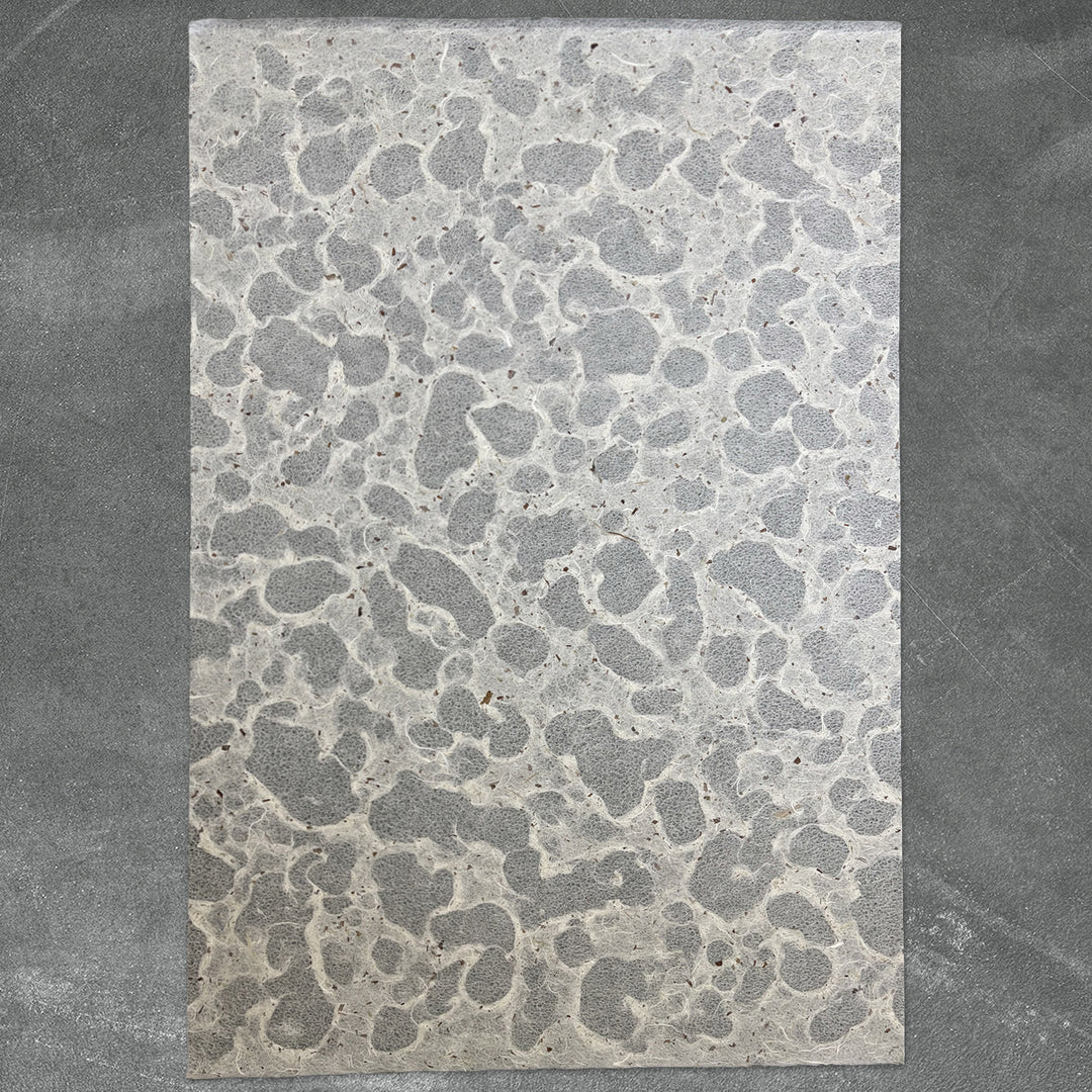 The Tidal Lace Kozo Paper (Chiri) from Kozo Studio is a rectangular sheet of sustainable, textured gray handmade paper with an irregular, speckled pattern, displayed on a darker gray background.
