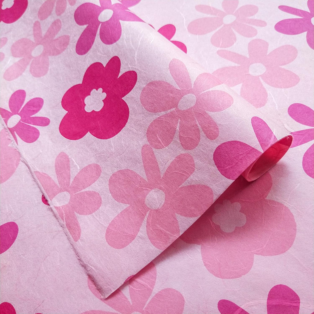 Two overlapping sheets of screen-printed handmade paper with lively floral designs in pink and fuchsia by Kozo Studio, made from traditional mulberry paper.