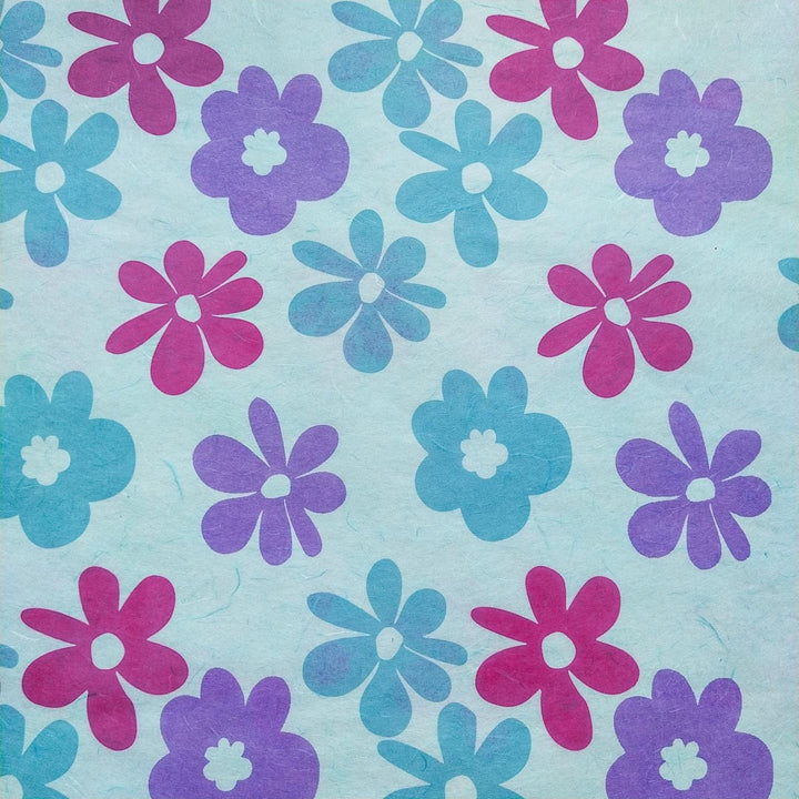 Handmade Caribbean floral mulberry paper from Kozo Studio, screen-printed with pink, purple, and blue flowers on a sky blue background.