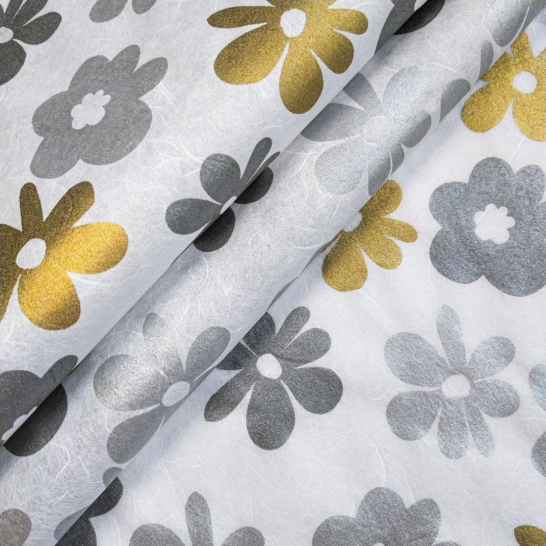 Close-up of handmade mulberry paper from Kozo Studio, screen-printed with tropical floral patterns in metallic gold and silver on a white Caribbean-inspired background.