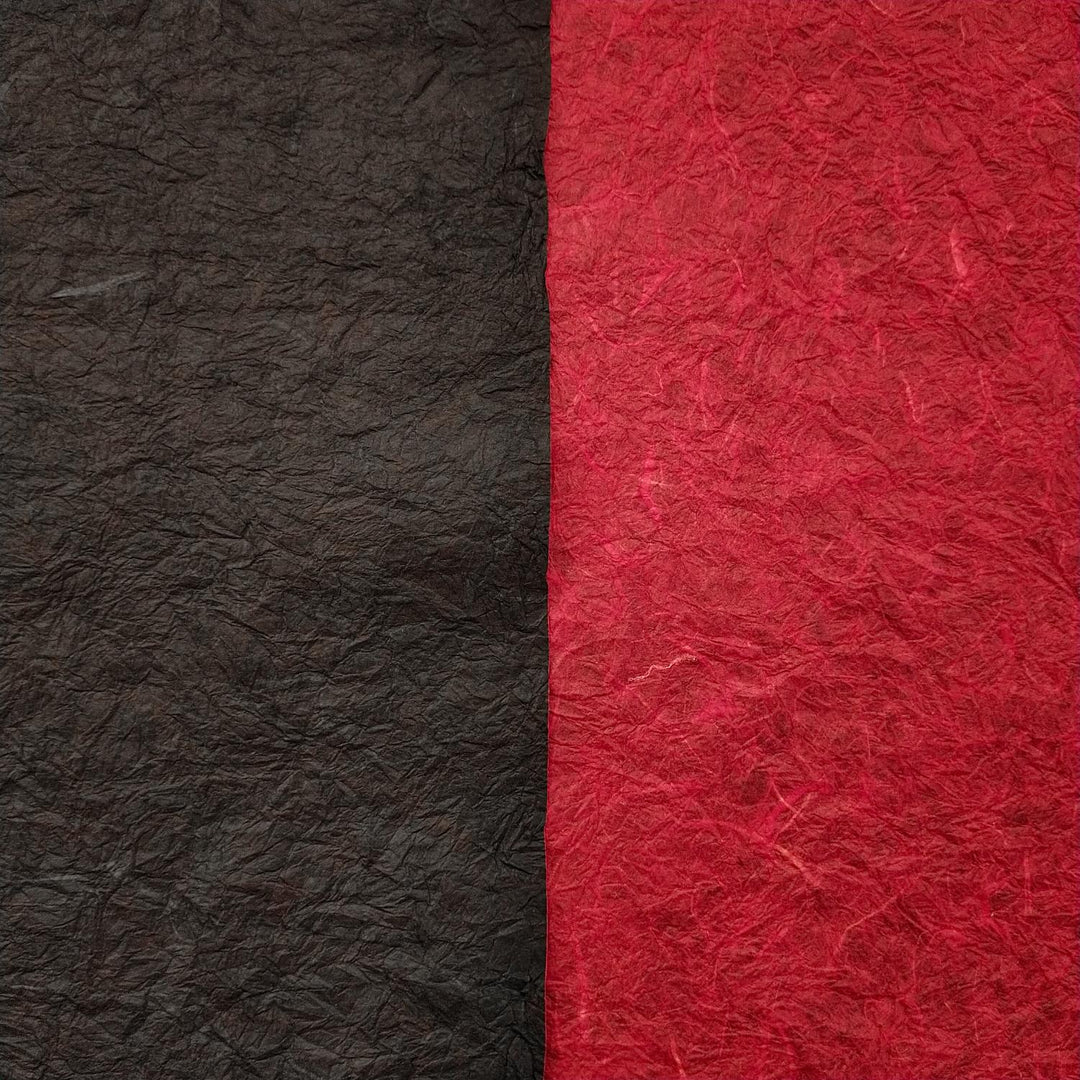 Textured handmade paper by Kozo Studio featuring vibrant red and black mulberry paper sheets, shown curled to display the double-sided Momigami design.