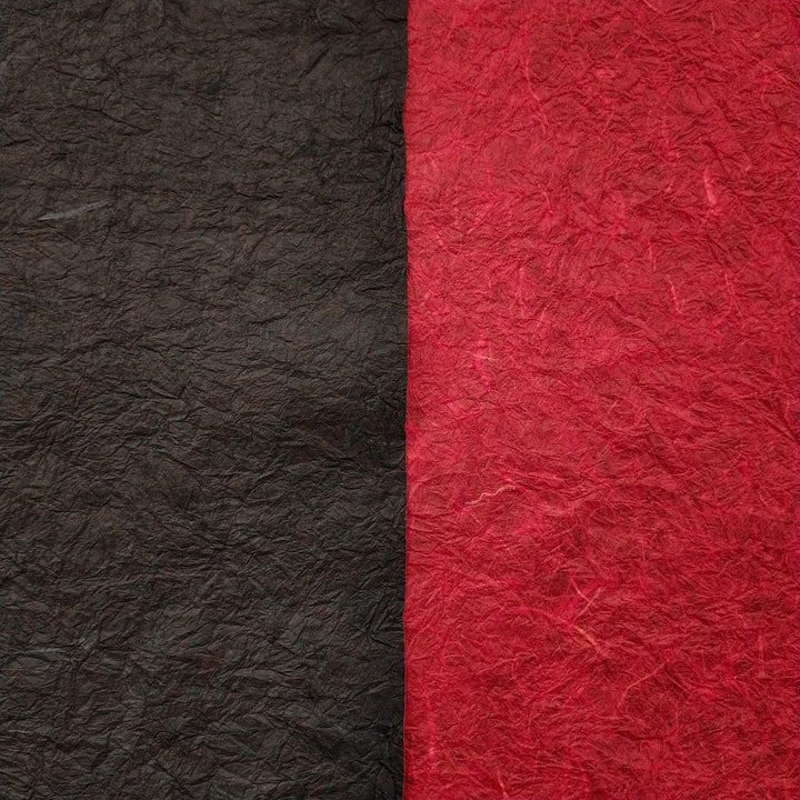 Textured handmade paper by Kozo Studio featuring vibrant red and black mulberry paper sheets, shown curled to display the double-sided Momigami design.