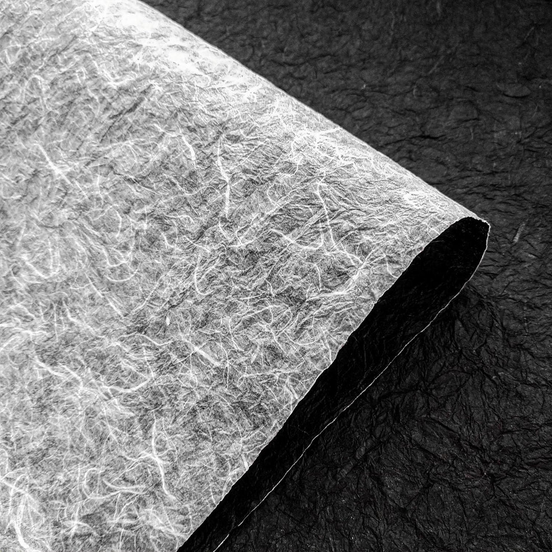 Textured black and white double-sided handmade paper from Kozo Studio, featuring crinkled mulberry paper fibers that highlight its artisanal quality.