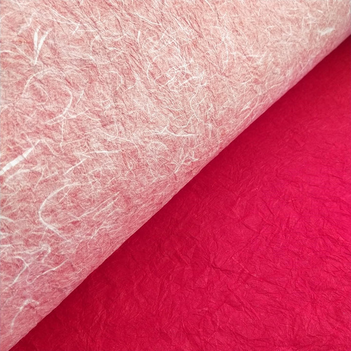 A close-up of crinkled handmade paper by Kozo Studio, crafted from mulberry fiber with a red and white dual-sided design, ideal for creative art projects.