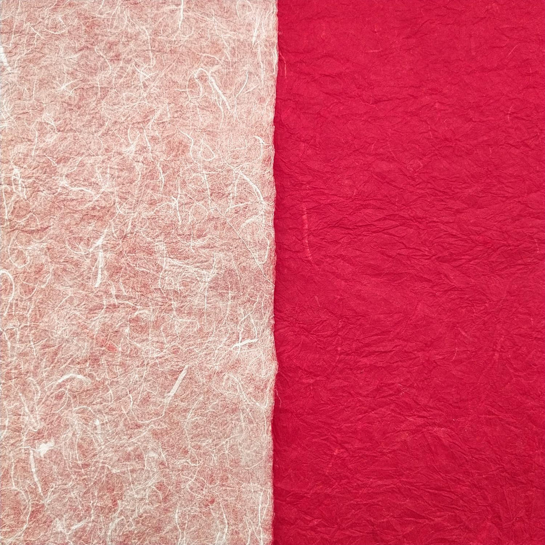 Textured layers of Momigami Kozo Paper from Kozo Studio displayed partially rolled, revealing the unique dual colors of this high-quality handmade paper.