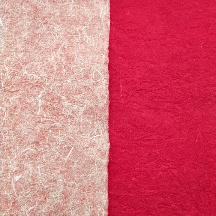 Textured layers of Momigami Kozo Paper from Kozo Studio displayed partially rolled, revealing the unique dual colors of this high-quality handmade paper.