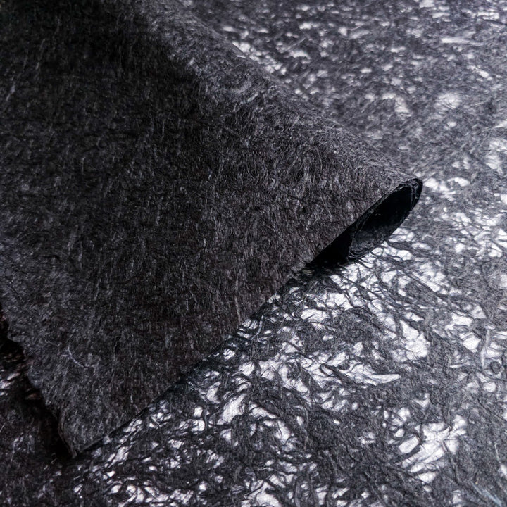 Close-up of black mulberry paper from Kozo Studio, showcasing its translucent handmade base with organic fiber strands, ideal for creative art and design projects.