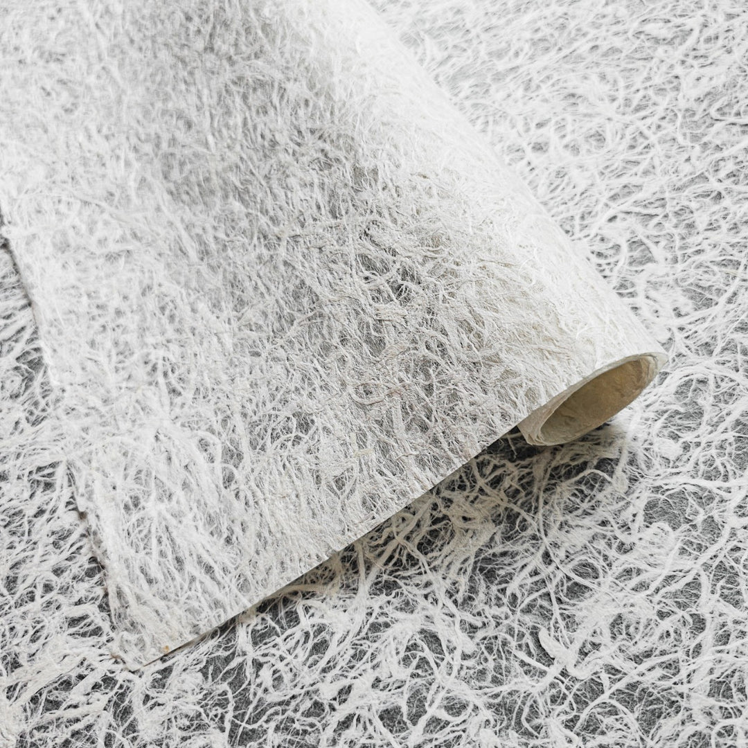 Delicate handmade mulberry paper from Kozo Studio with translucent texture and natural fiber strands, ideal for light-filled art projects and decor.