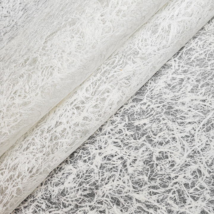 Close-up of Fiber Veil Kozo Paper (White) by Kozo Studio, featuring a textured, fibrous appearance with a delicate web-like pattern. This layered mulberry paper highlights intricate details and offers a slightly translucent quality.