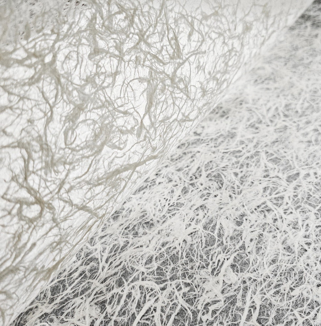 Handmade paper from Kozo Studio crafted with mulberry fiber, showcasing a soft, glowing translucency and elegant organic texture.