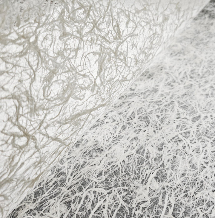Handmade paper from Kozo Studio crafted with mulberry fiber, showcasing a soft, glowing translucency and elegant organic texture.