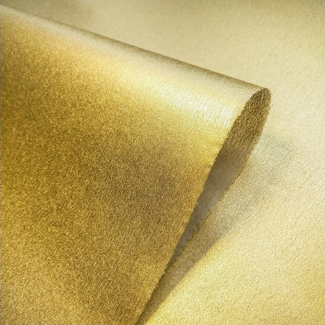 Artistic shot of metallic kozo handmade paper from Kozo Studio, with a textured mulberry surface and golden glow.