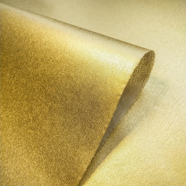 Artistic shot of metallic kozo handmade paper from Kozo Studio, with a textured mulberry surface and golden glow.