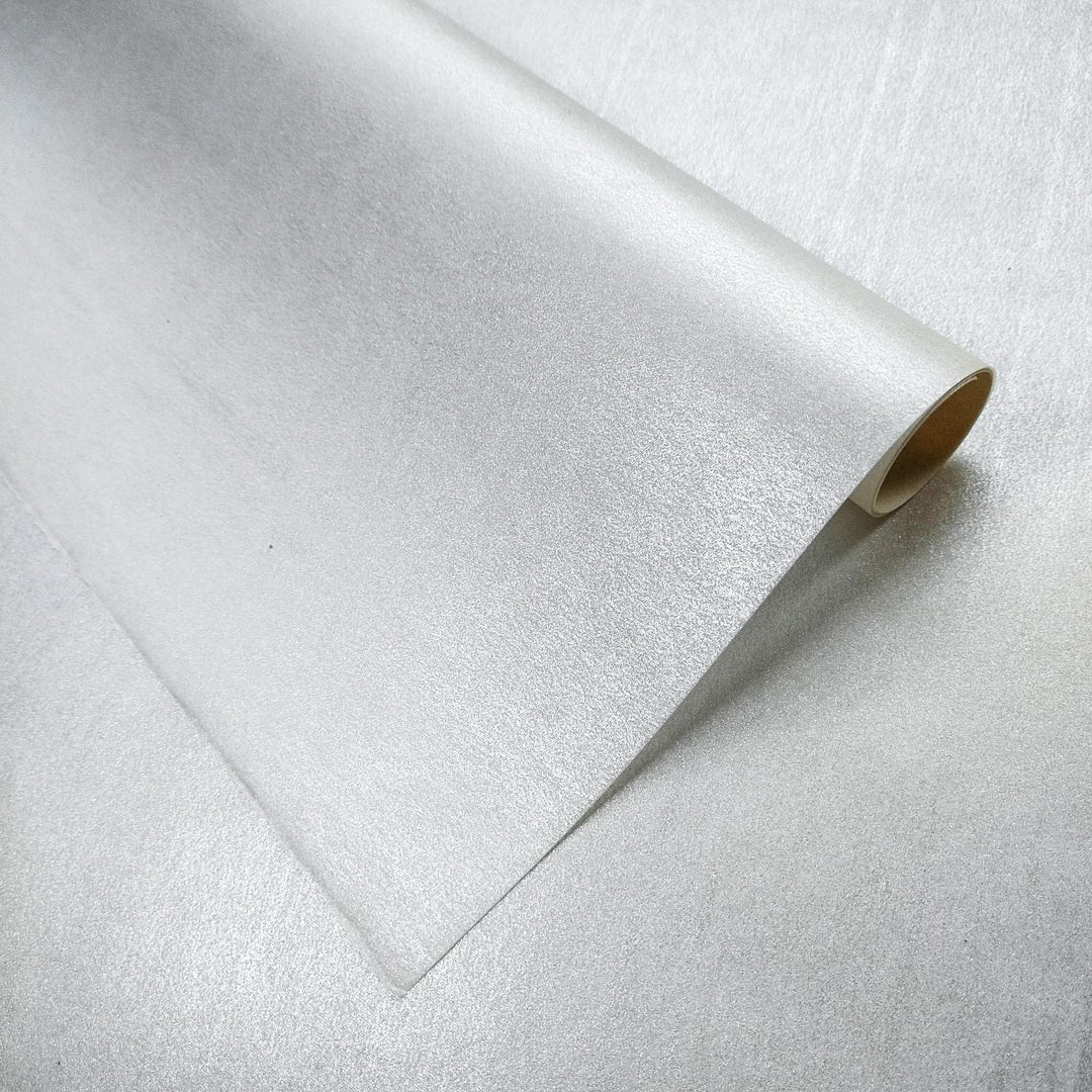 Gleaming Metallic Kozo paper unrolled on a surface, showcasing its shiny mulberry paper texture and elegant handmade paper finish from Kozo Studio.