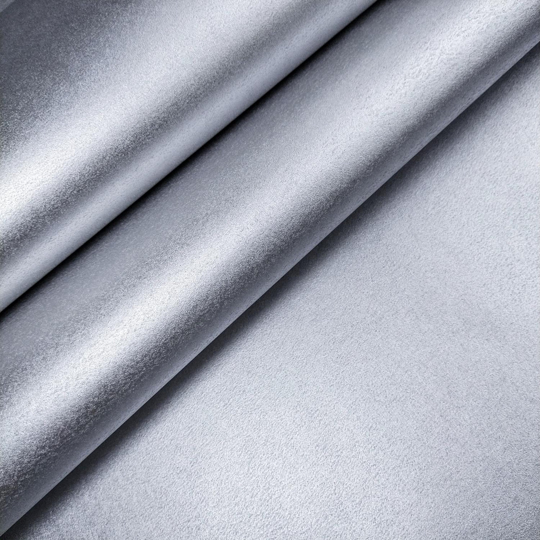 Single sheet of silver mulberry paper by Kozo Studio, curled at the corner and photographed against a grey background to emphasize its handmade paper quality.