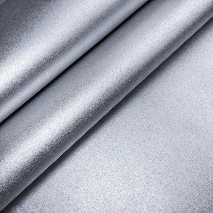 Single sheet of silver mulberry paper by Kozo Studio, curled at the corner and photographed against a grey background to emphasize its handmade paper quality.