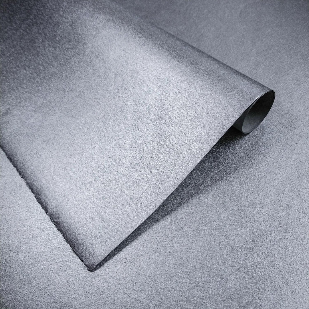 Close-up of metallic silver mulberry paper made from kozo fiber by Kozo Studio, highlighting its handmade paper texture and curled corner.