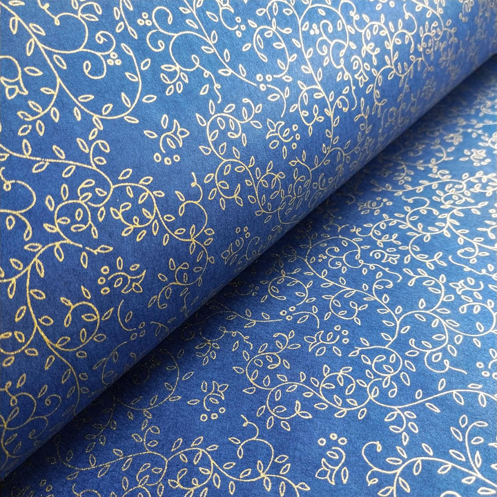 Kozo Studio handmade mulberry paper in a close-up showing gold floral tendrils on a smooth blue background with a folded sheet emphasizing the design continuity.
