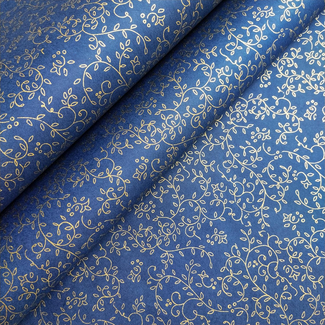 Detailed shot of screen-printed blue handmade paper by Kozo Studio featuring gold botanical patterns on premium mulberry paper with a fold accentuating the fine texture.