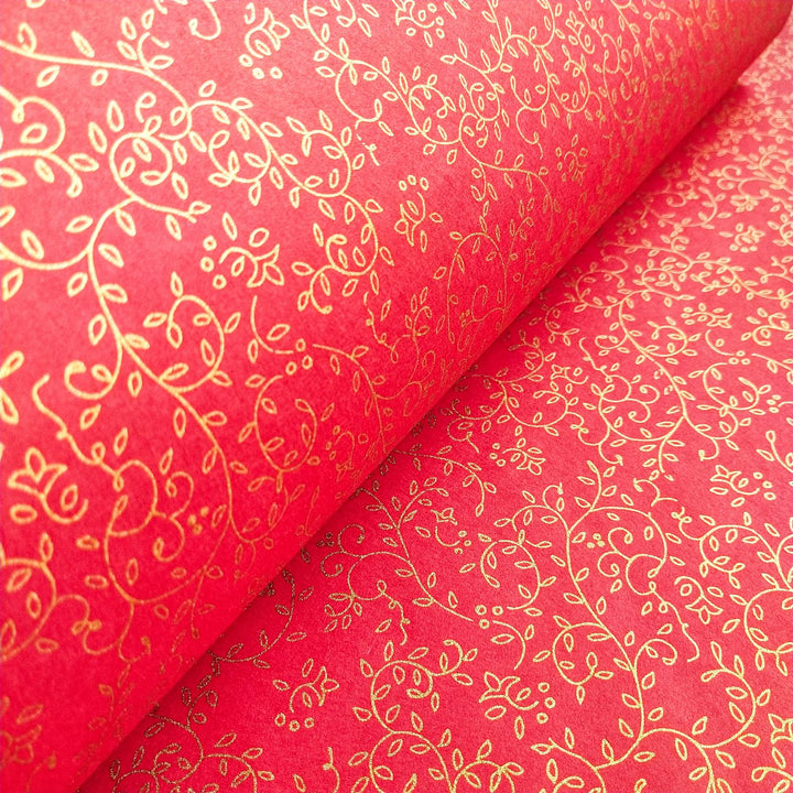 Close-up of Kozo Studios Grapevine Screen-printed Kozo Paper Red, featuring intricate gold floral patterns on a rich red background with swirling vines and small leaves for a festive look.