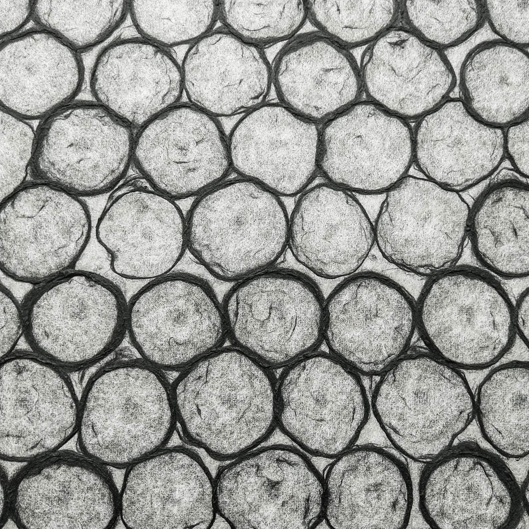 Kozo Studio's handmade paper with beehive-like overlapping circles in black, highlighting the paper's translucency and suitability for interior and art uses.