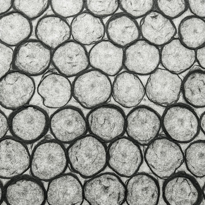 Kozo Studio's handmade paper with beehive-like overlapping circles in black, highlighting the paper's translucency and suitability for interior and art uses.