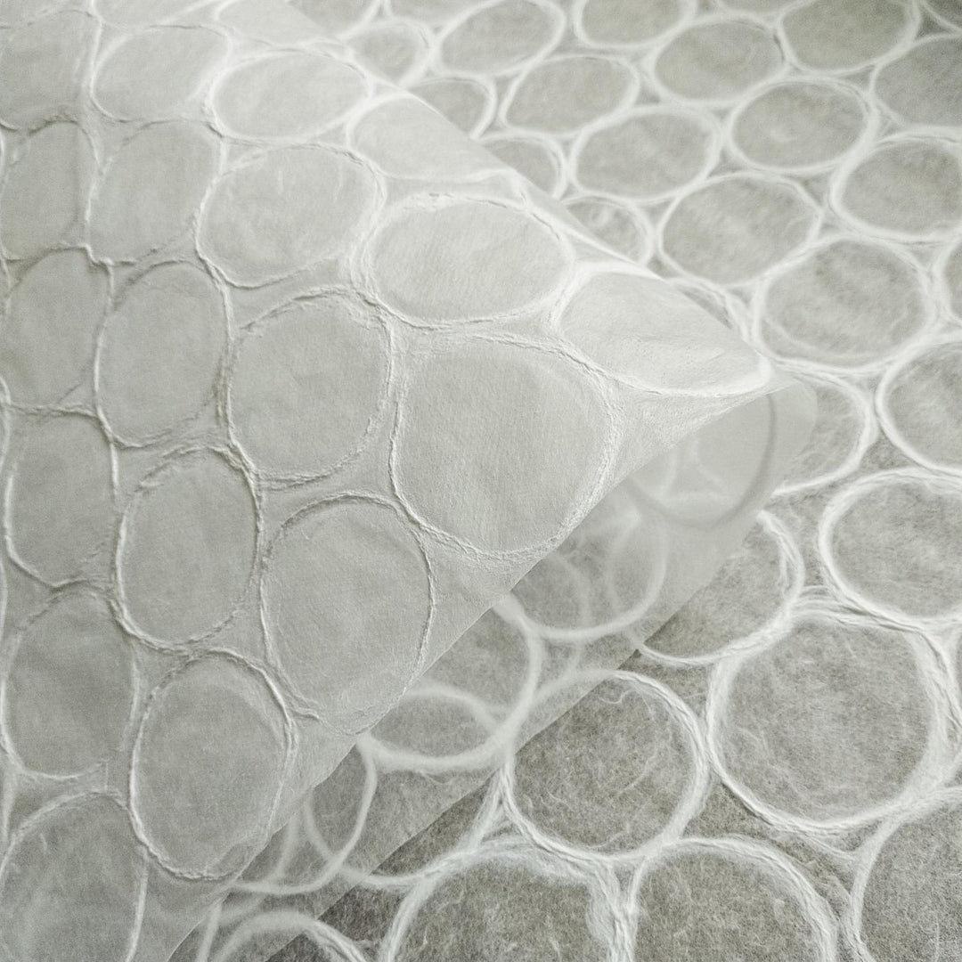 Artistic detail of Kozo Studio mulberry paper with an abstract pattern of round shapes and fine fibers, suitable for decorative and functional handmade paper crafts.