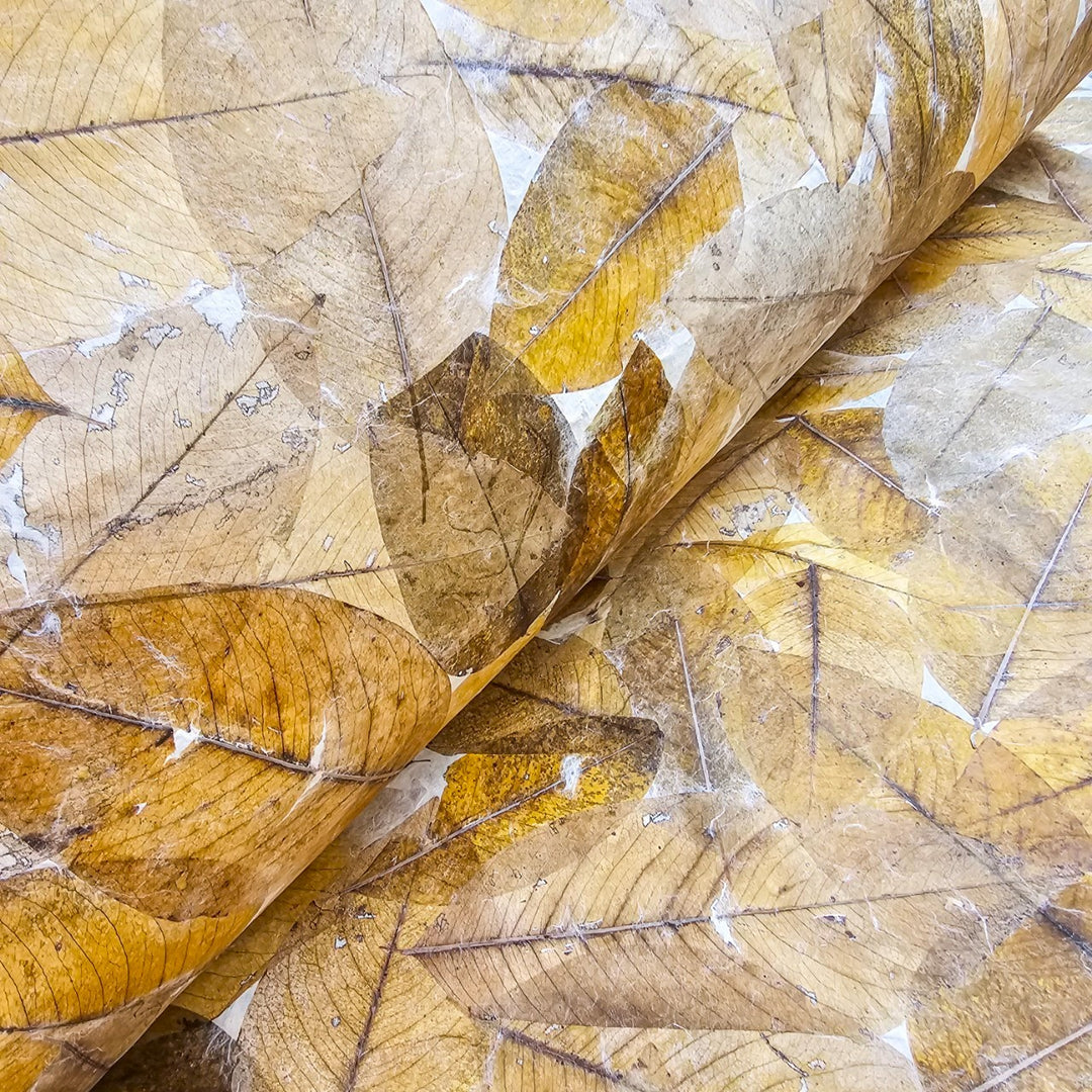 A close-up of Handmade Cassia Leaf Kozo Mulberry Paper by Kozo Studio reveals layers of dry leaves in shades of brown, gold, and beige. The intricate vein patterns create a natural texture.