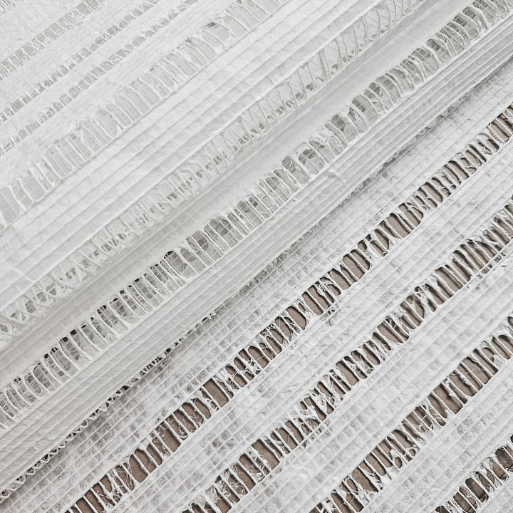 Close-up of Handmade Geloma Kozo Paper (White) from Kozo Studio, featuring white textured fabric with horizontal openwork stripes and thin vertical grid lines like delicate rice paper. Lightweight and slightly sheer, this airy pattern adds elegance to any setting.