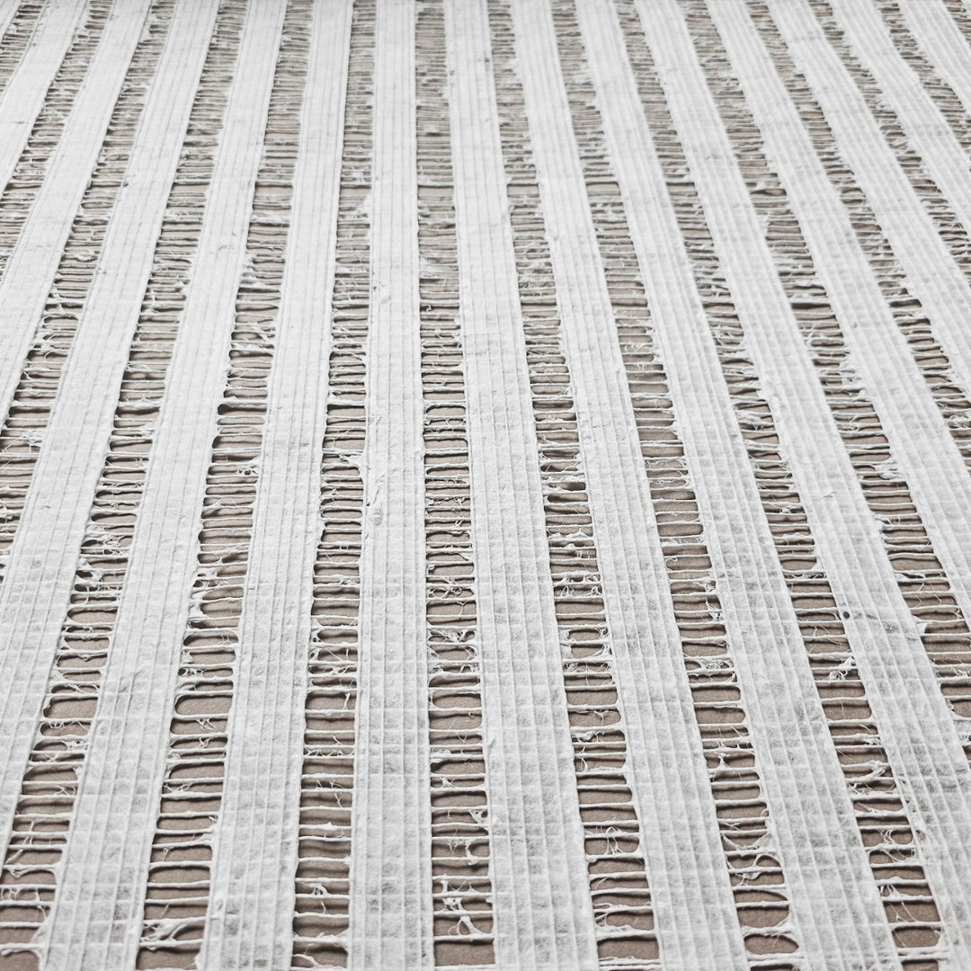 Close-up of Handmade Geloma Kozo Paper (White) by Kozo Studio, featuring frayed and ripped textures with vertical, evenly spaced rows. The delicate grid-like pattern allows the background to show through its rice paper-like tears.