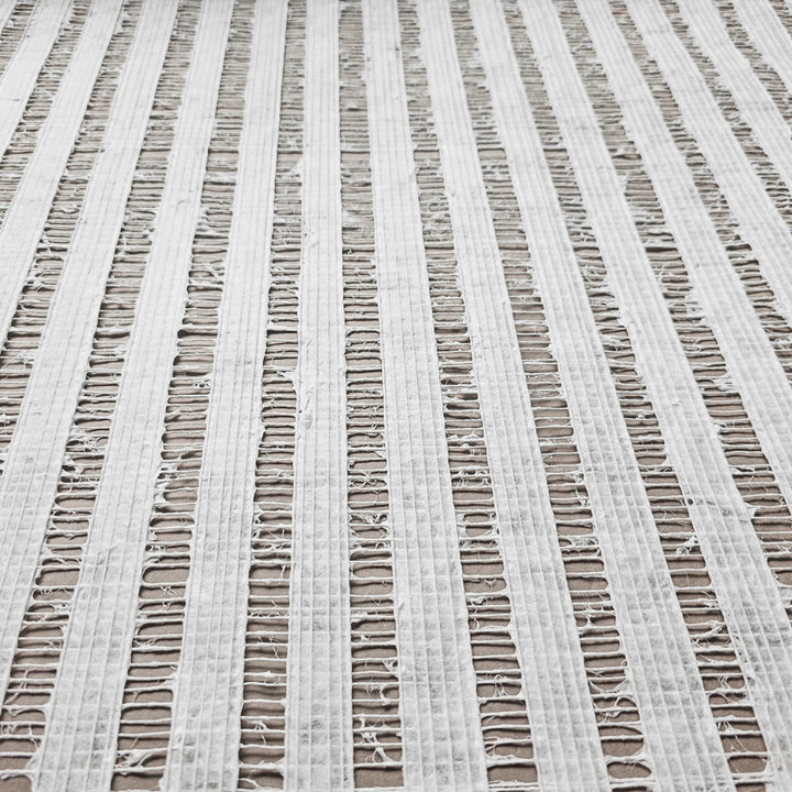 Close-up of Handmade Geloma Kozo Paper (White) by Kozo Studio, featuring frayed and ripped textures with vertical, evenly spaced rows. The delicate grid-like pattern allows the background to show through its rice paper-like tears.