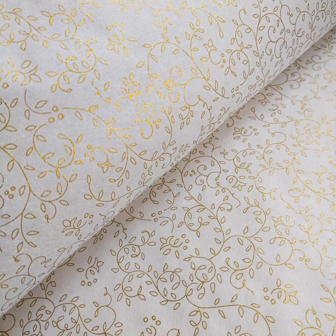 A roll of handmade paper from Kozo Studio featuring a gold grapevine pattern on soft white mulberry paper, perfect for elegant art and design projects.