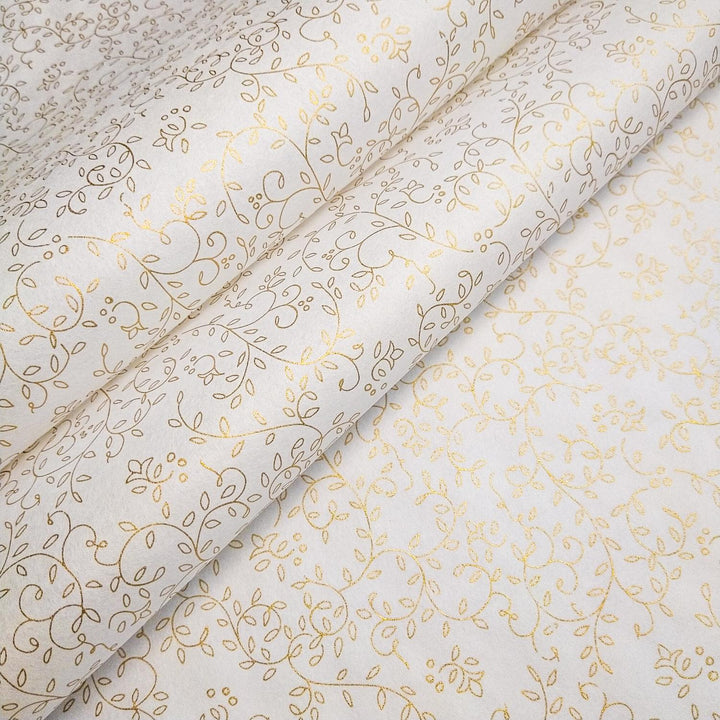 Close-up of Kozo Studio screen-printed handmade paper unrolled to show a refined gold floral pattern across white mulberry paper.