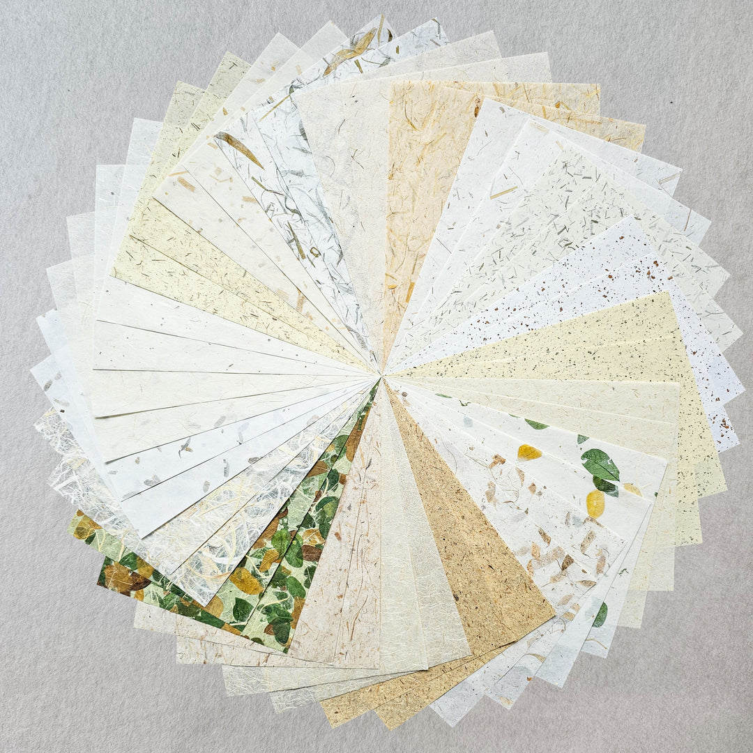 A flat lay image of Kozo Studio’s premium handmade paper collection, featuring 20 types of mulberry paper made with kozo pulp and infused with organic elements like jute, sugarcane, and tamarind.