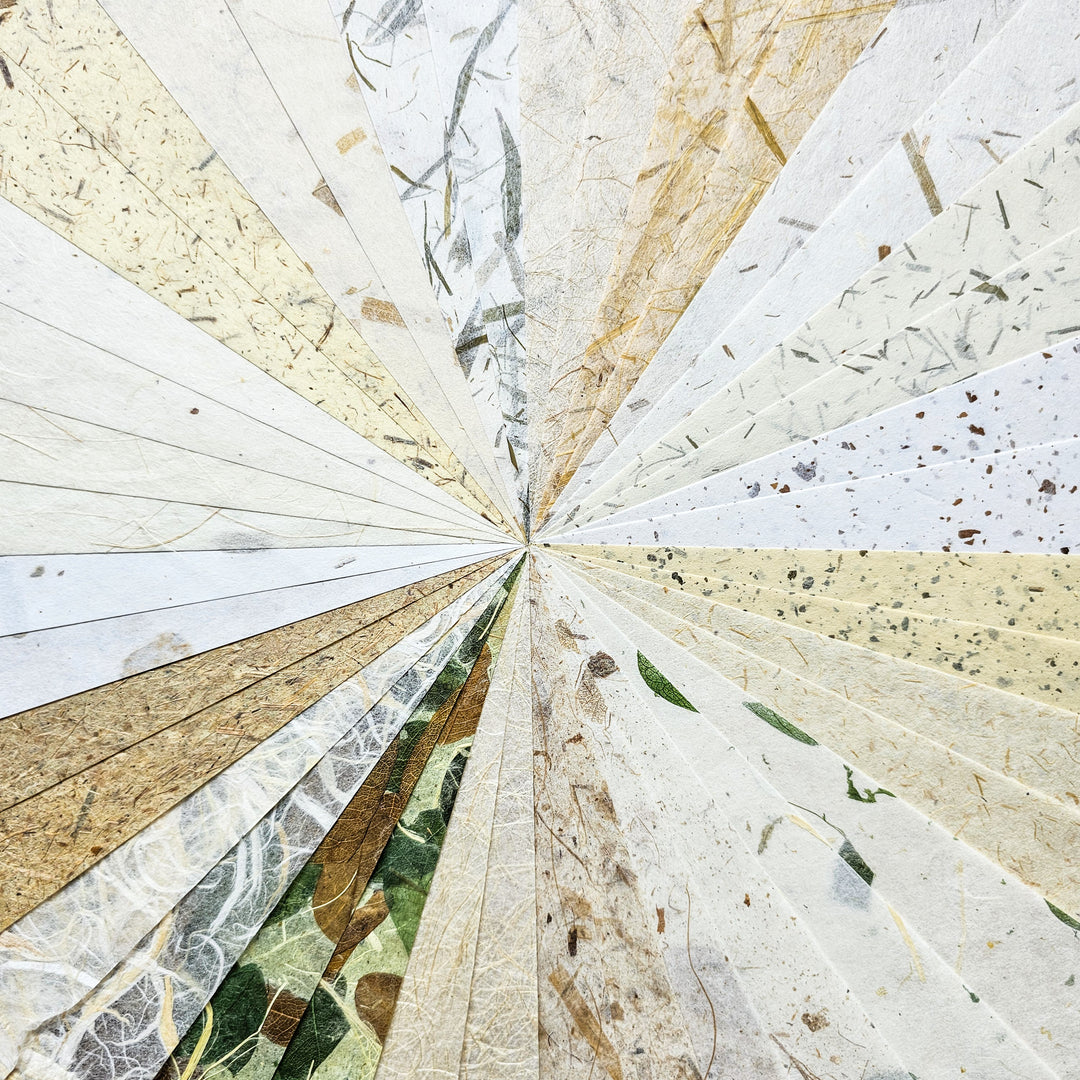 The Kozo Studio A4 Natural Inclusion Mulberry Paper Pack (40 sheets, 20 designs) showcases radial textured paper samples, including mulberry and rice papers in white, beige, and earthy tones. Some feature natural fibers and speckles for an organic pattern converging at the center.