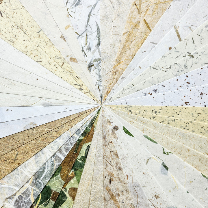 The Kozo Studio A4 Natural Inclusion Mulberry Paper Pack (40 sheets, 20 designs) showcases radial textured paper samples, including mulberry and rice papers in white, beige, and earthy tones. Some feature natural fibers and speckles for an organic pattern converging at the center.