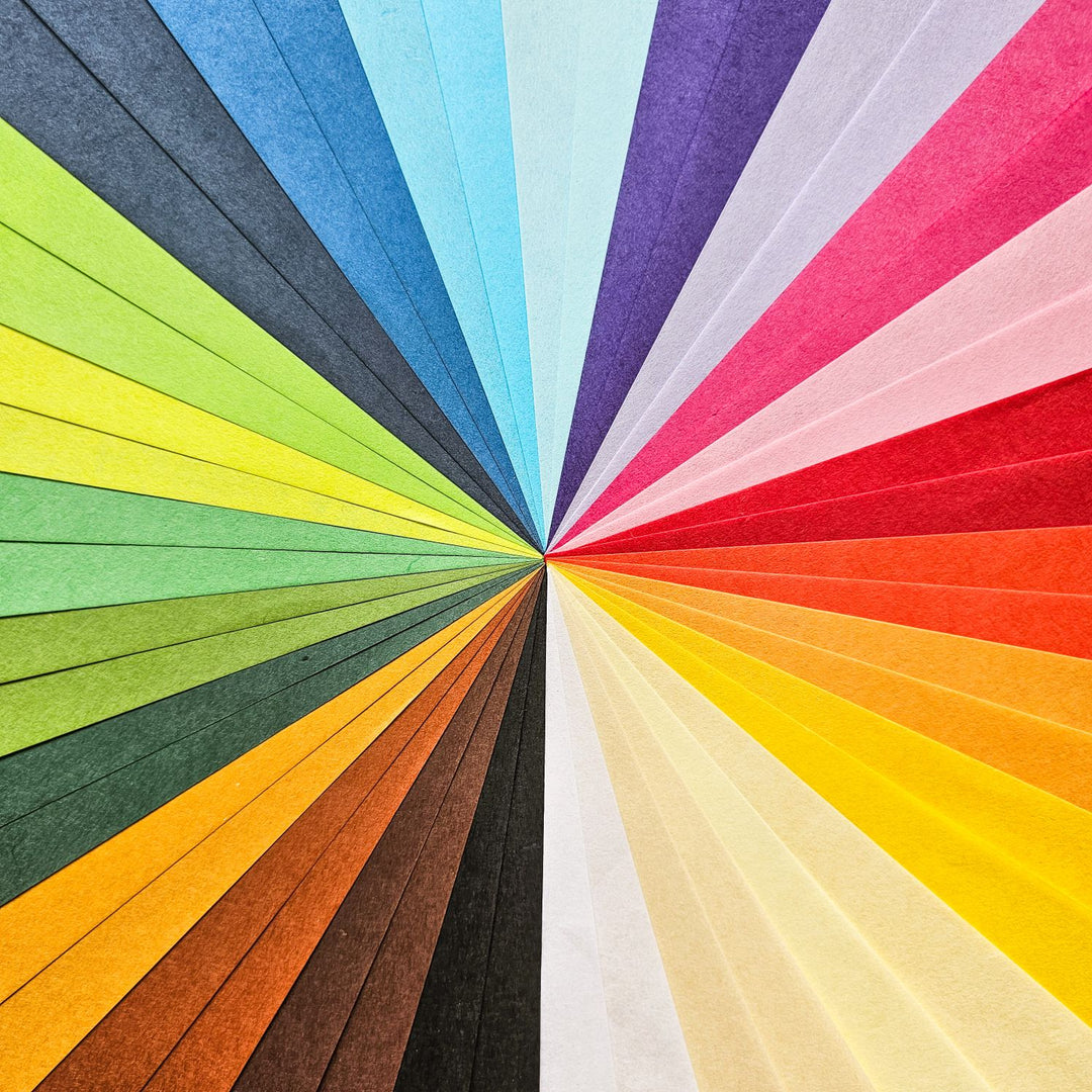 Handmade mulberry paper collection by Kozo Studio, displayed in a rainbow of 24 shades, perfect for creative uses like scrapbooking, invitations, and detailed paper art.