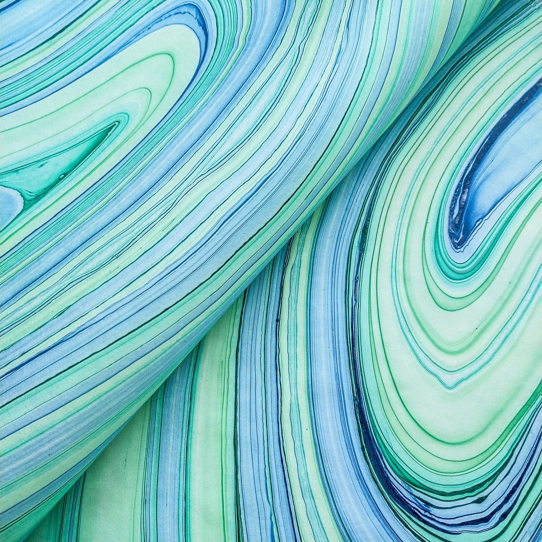 Folded edge of Marble Kozo Paper by Kozo Studio showing the seamless transition of blue and green marble lines on artisanal handmade mulberry paper.