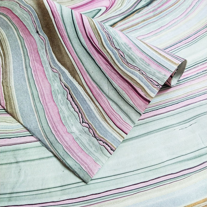 Close-up of Marble Kozo Paper Design 5 by Kozo Studio, showcasing swirling pink, green, brown, and cream patterns on handmade mulberry paper, with a lifted corner revealing wave-like textures.