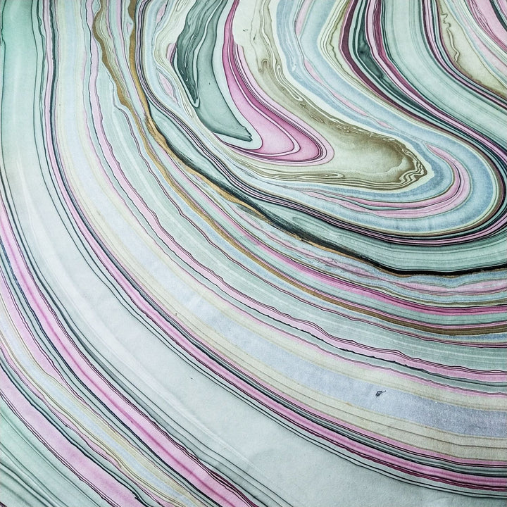 Vibrant marbled kozo paper captured in a high-resolution photo, showing pink, green, and cream waves from Kozo Studio's handmade mulberry paper collection.
